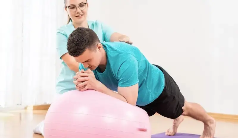 Krankengymnastik nach einer OP der Diskuhernie - Mann macht Übungen auf einem Gummiball