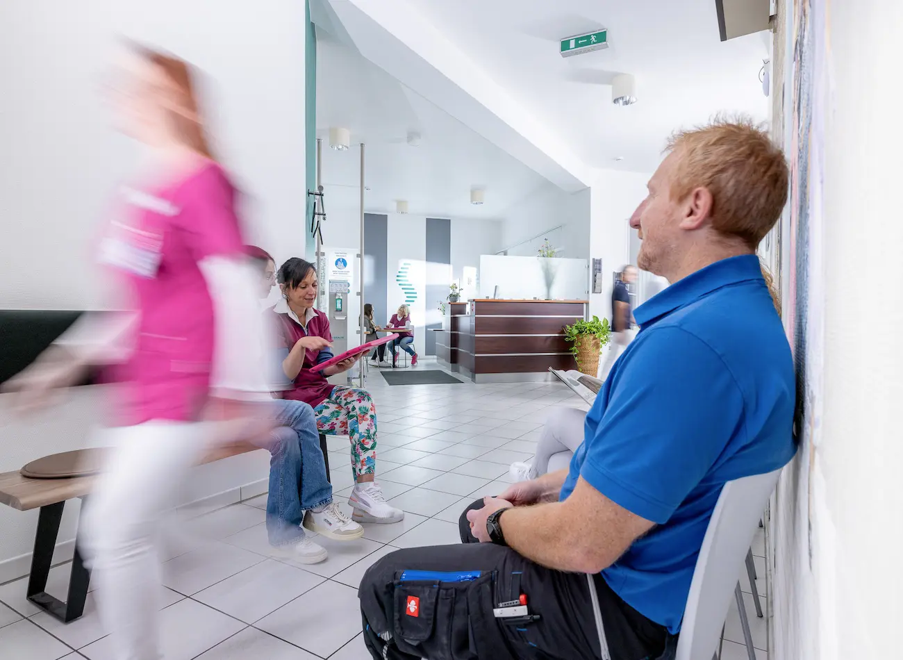 Mvz Bandscheibenpraxis Gensingen, Wartebereich. Mann im blauen Tshirt sitzt auf einem Stuhl.